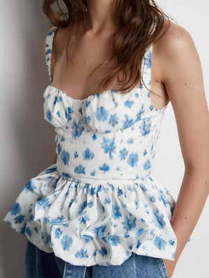 White peplum top with blue floral print, sweetheart neckline, and ruffled hem.