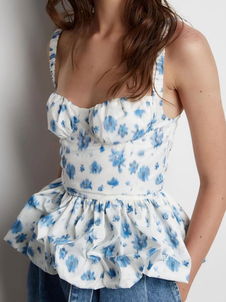White peplum top with blue floral print, sweetheart neckline, and ruffled hem.