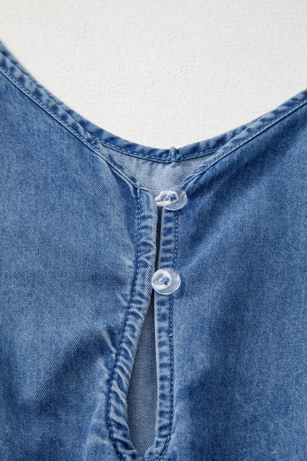 Medium wash denim romper with V-neck and button detail