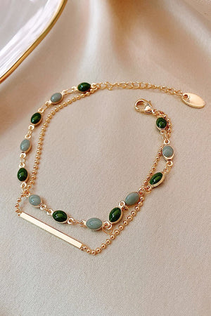 Dual chain bracelet in gold with green and grey stones and a bar accent