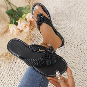 Black braided thong sandals with 3D floral accents and elegant details.