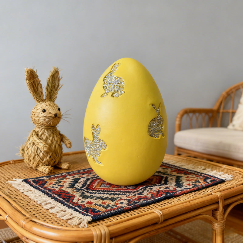 Yellow Easter egg decor with glitter bunny cutouts and a straw bunny.