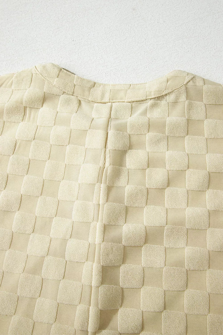 Textured cream checkered sleeveless romper with band collar detail.