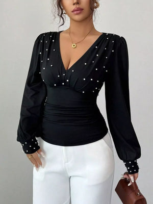 Black ruched V-neck blouse with pearl embellishments on neckline and cuffs.