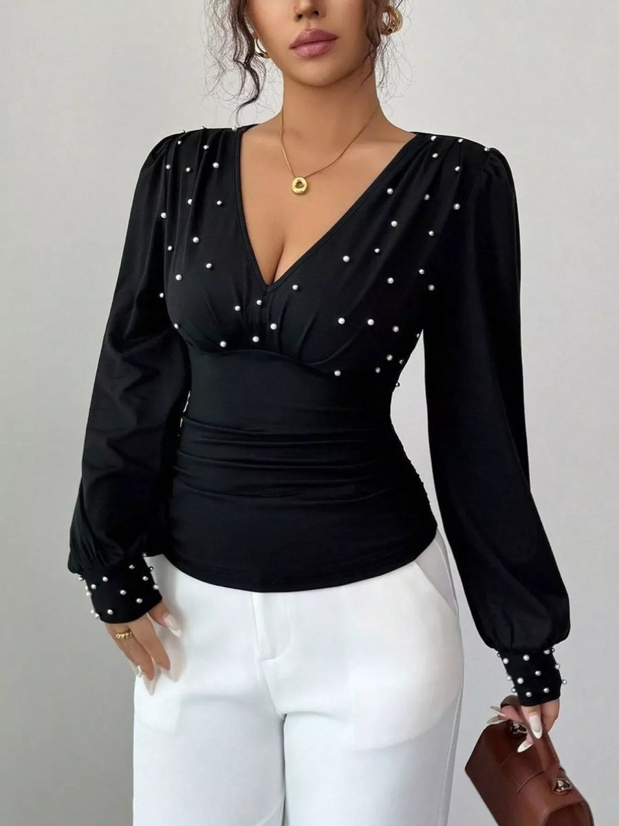 Black ruched V-neck blouse with pearl embellishments on neckline and cuffs.