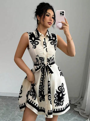 Sleeveless button-down shirt dress in black and white print with tie waist and ruching detail.