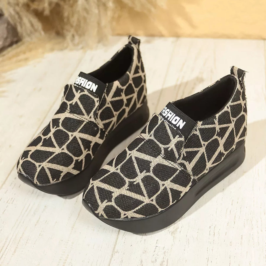 Black and beige geometric patterned slip-on sneakers with platform soles.