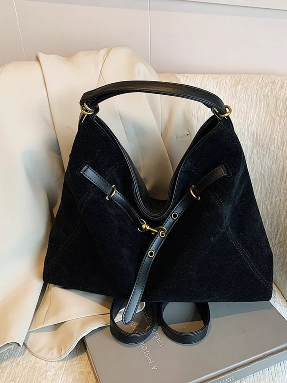 Sleek black slouchy crossbody bag with gold accents and adjustable strap.