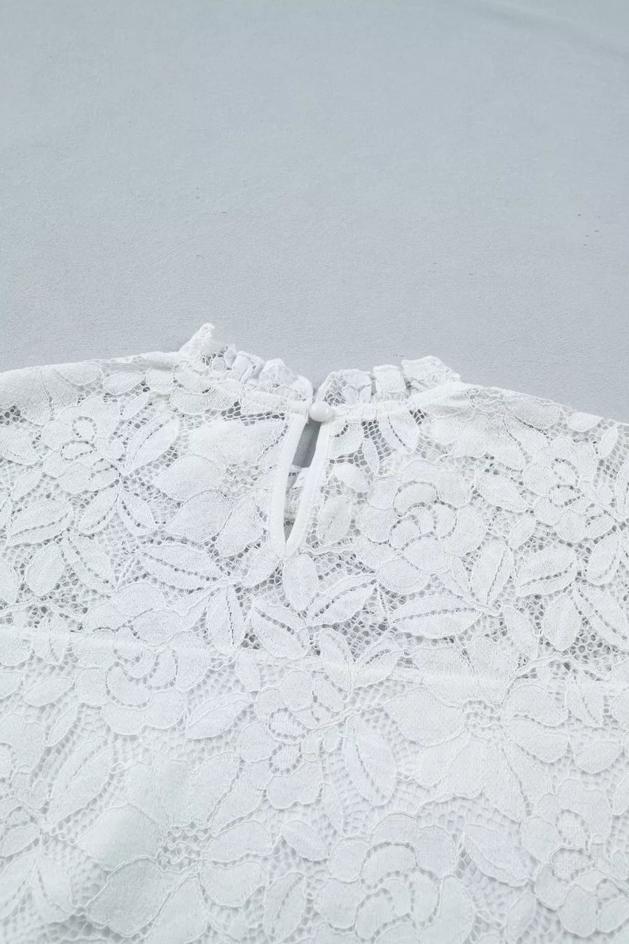 White lace blouse with ruffled neckline and tie closure detail