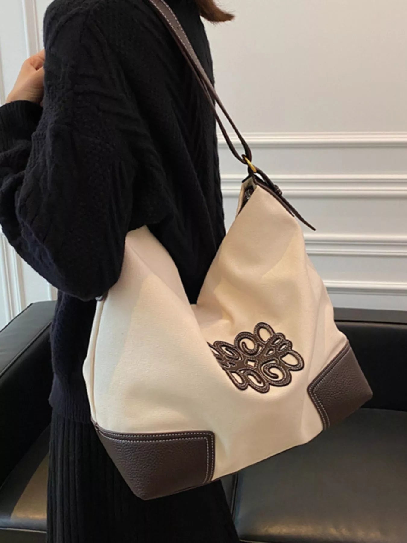 White canvas tote bag with brown leather trim and embroidered detail