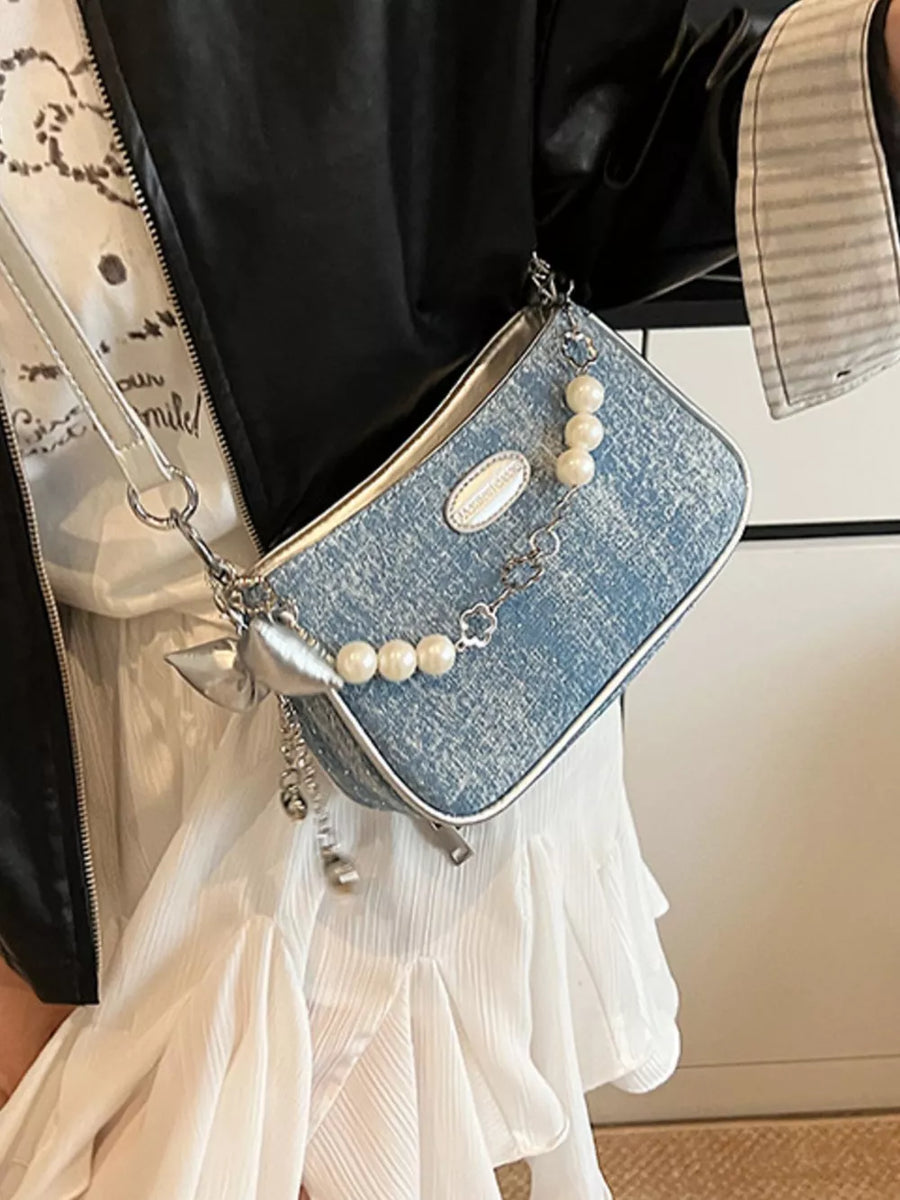 Denim shoulder bag with pearl chain and clover charm detail.