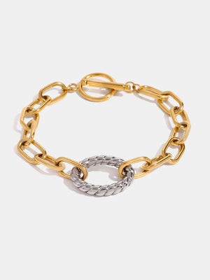 Two-tone chain link toggle bracelet with a textured oval center in gold and chrome.