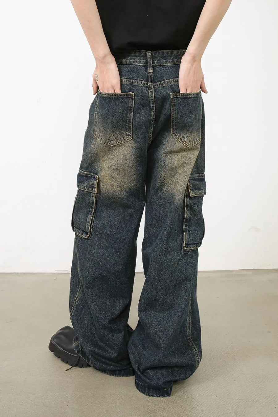 Distressed dark wash denim wide-leg cargo pants with zip pockets and a relaxed fit.