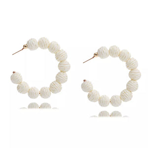 Raffia grass C-hoop earrings in beige with textured spherical beads and gold posts.