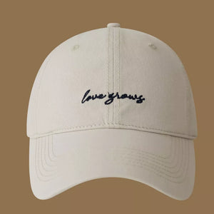 Apricot cotton baseball cap with embroidered "love grows" text