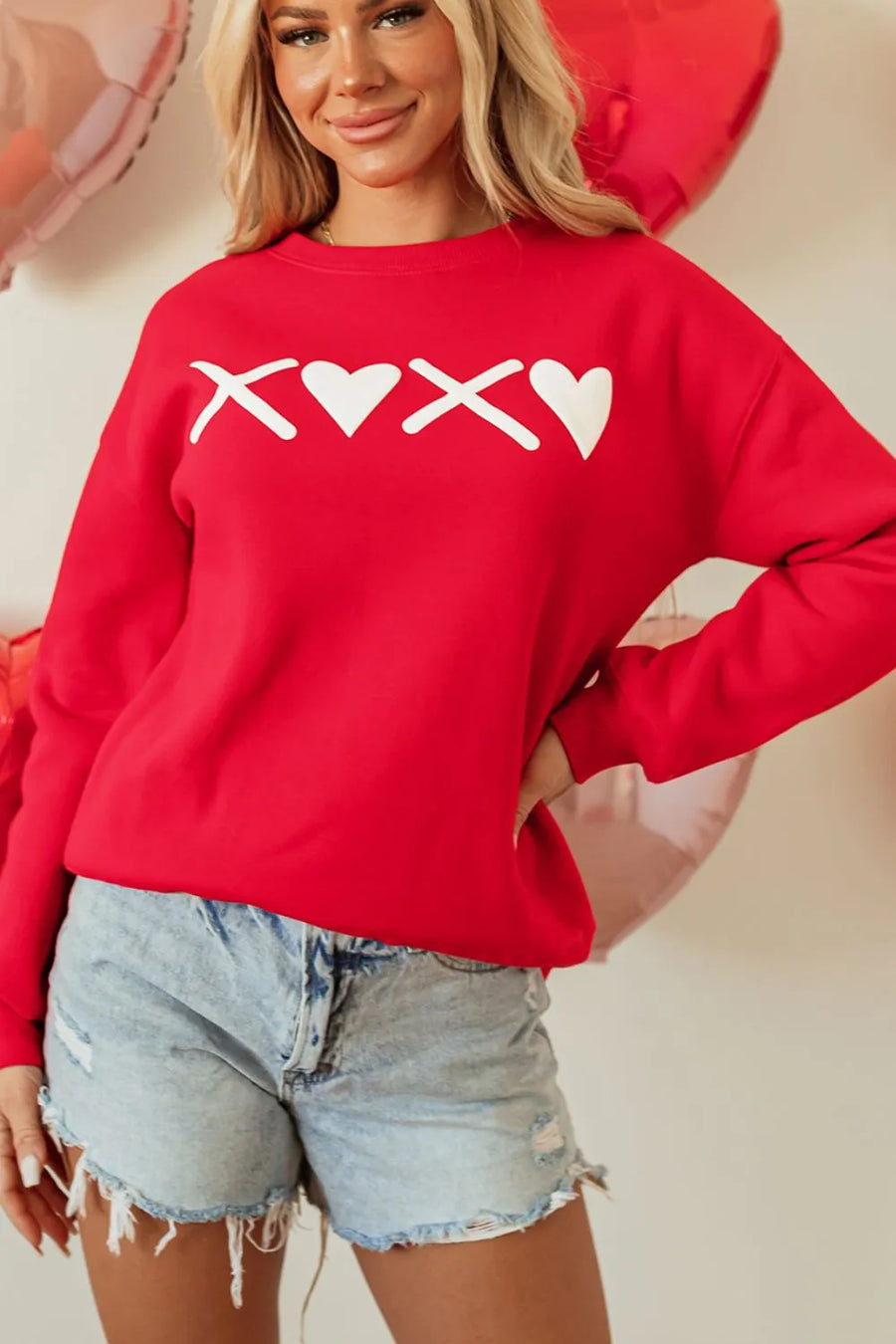 Red crewneck sweatshirt with white XOXO graphic and hearts, long sleeves.