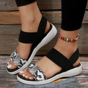 Geometric print elastic strap sandals with black straps and white snake print toe band.
