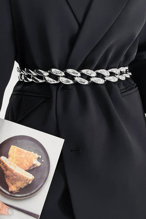 Silver sculptural chain waist belt with acrylic links, worn over a black blazer.