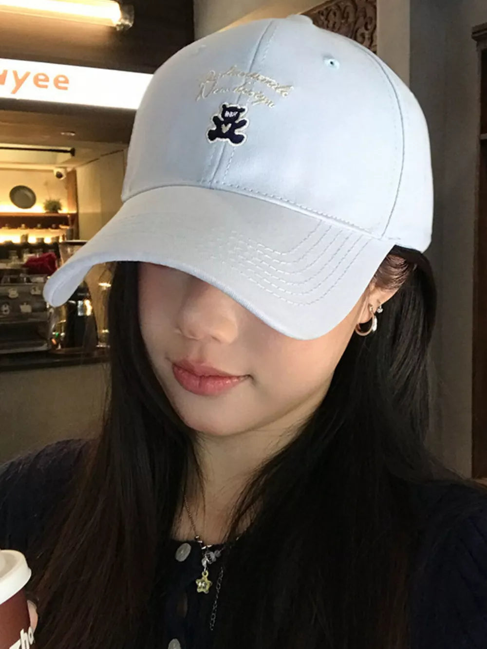 Light blue baseball cap with teddy bear embroidery and script text detail