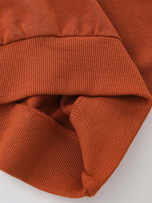 Rust cotton sweatshirt detail showing ribbed cuffs and hem.