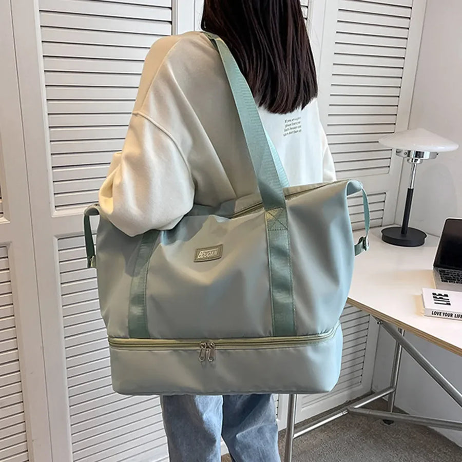 Dual-compartment travel tote in Dusty Blue with metallic trim and green straps.