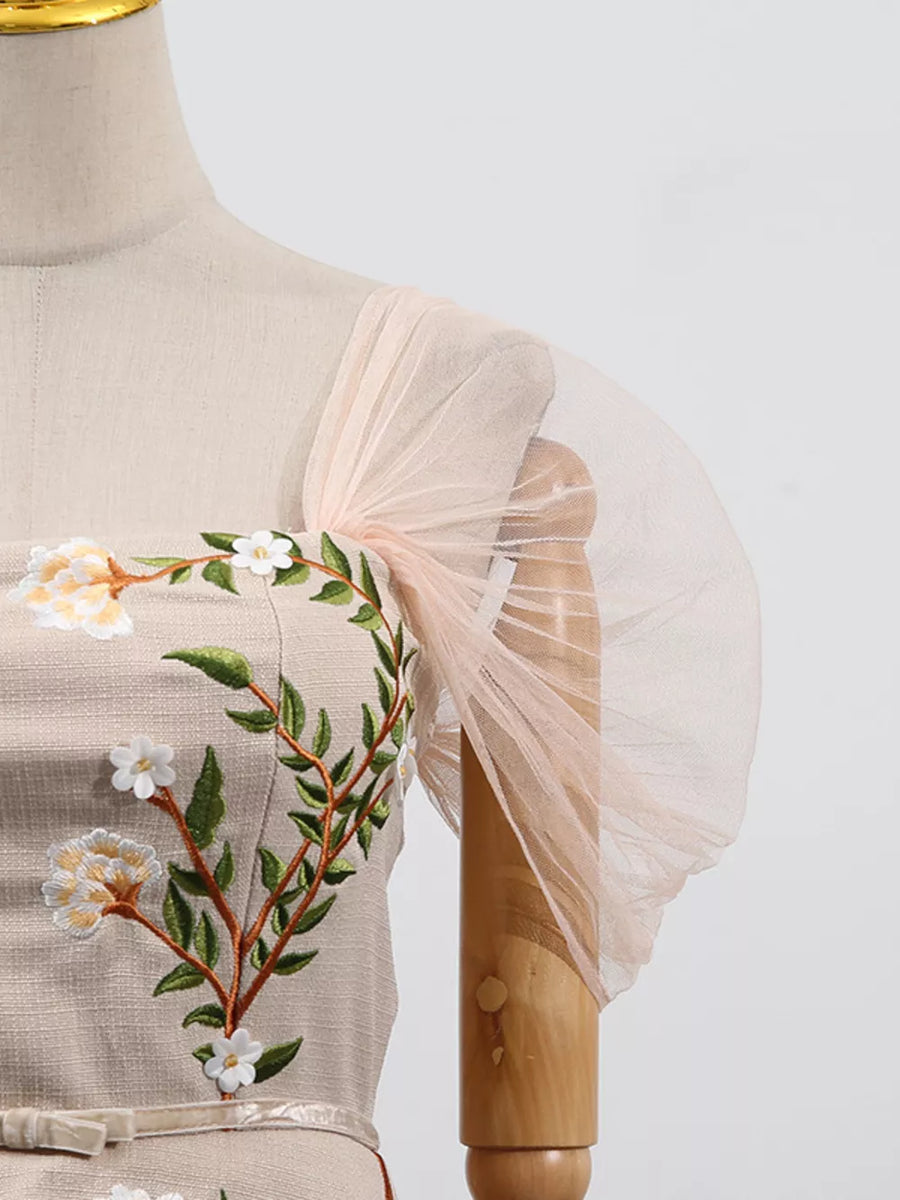Embroidered midi dress with sheer puff sleeves and floral detail.