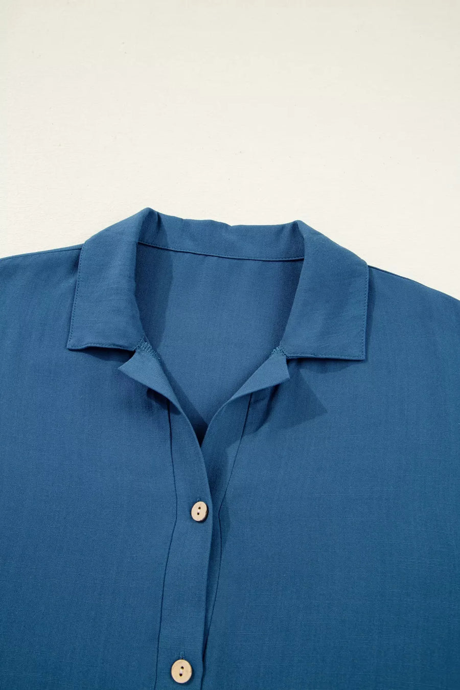 Blue linen blend collared button-up shirt with subtle vertical seams and light wood buttons.