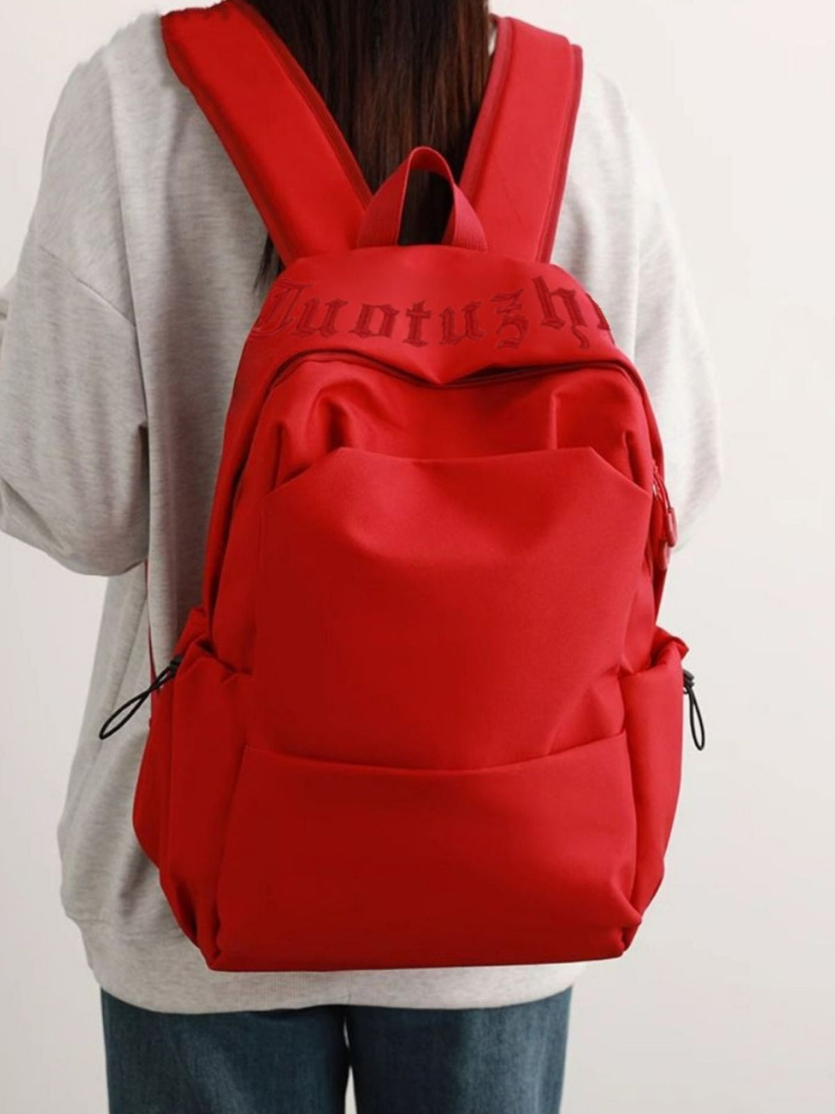 Red nylon drawstring backpack with padded straps and embossed logo detail
