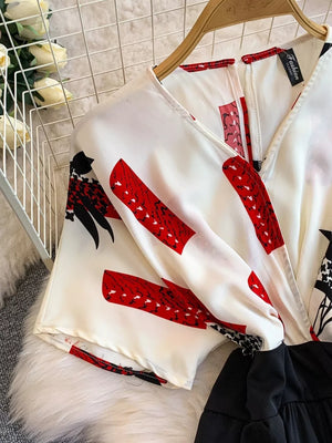 White abstract print wide-leg romper with V-neck and short sleeves.