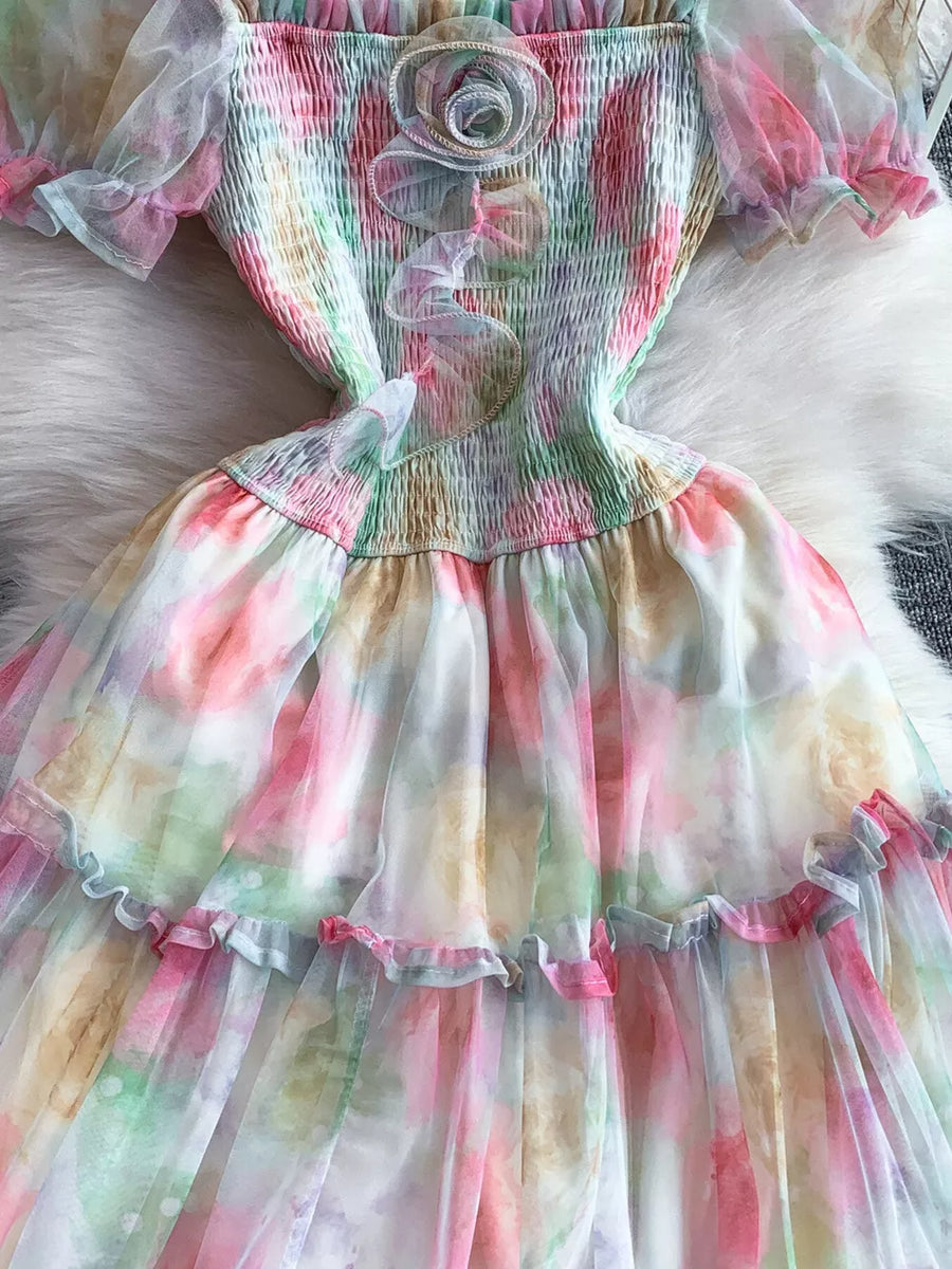 Floral tiered midi dress with smocked bodice and sheer sleeves in a pastel tie-dye print.