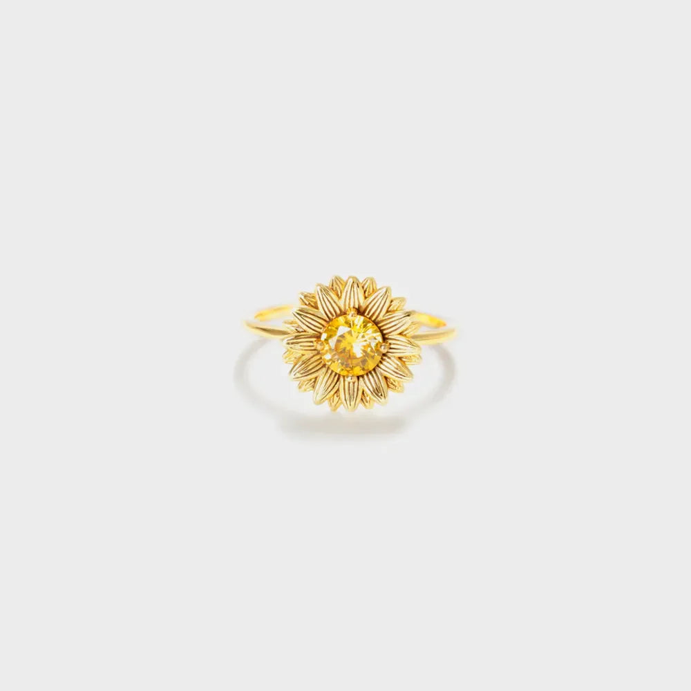 Gold sunflower ring with yellow gemstone center and detailed petals.