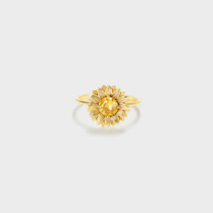 Gold sunflower ring with yellow gemstone center and detailed petals.