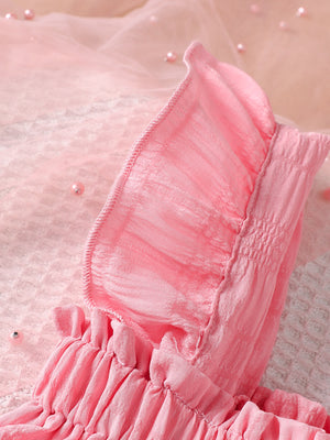 Pink baby top and pants set with delicate ruffles and smocking detail.