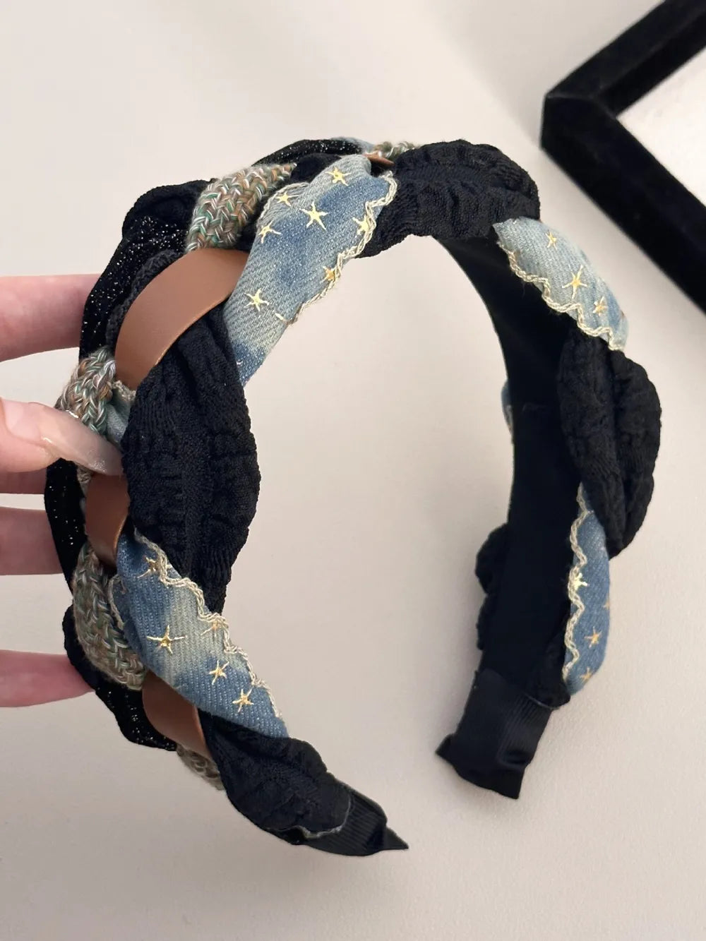 Black braided headband with denim starburst pattern and brown leatherette accents