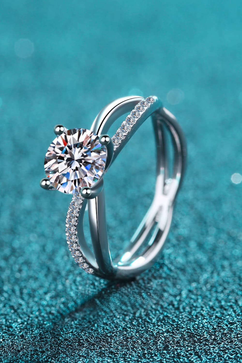 Silver crossover ring with solitaire moissanite and pavé accent stones.