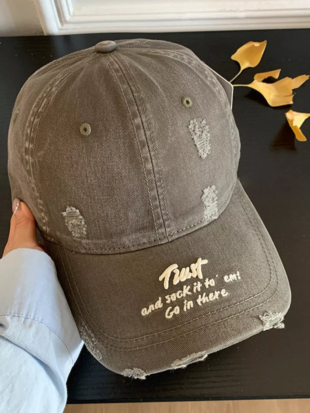 Embroidered distressed baseball hat in grey with white text.