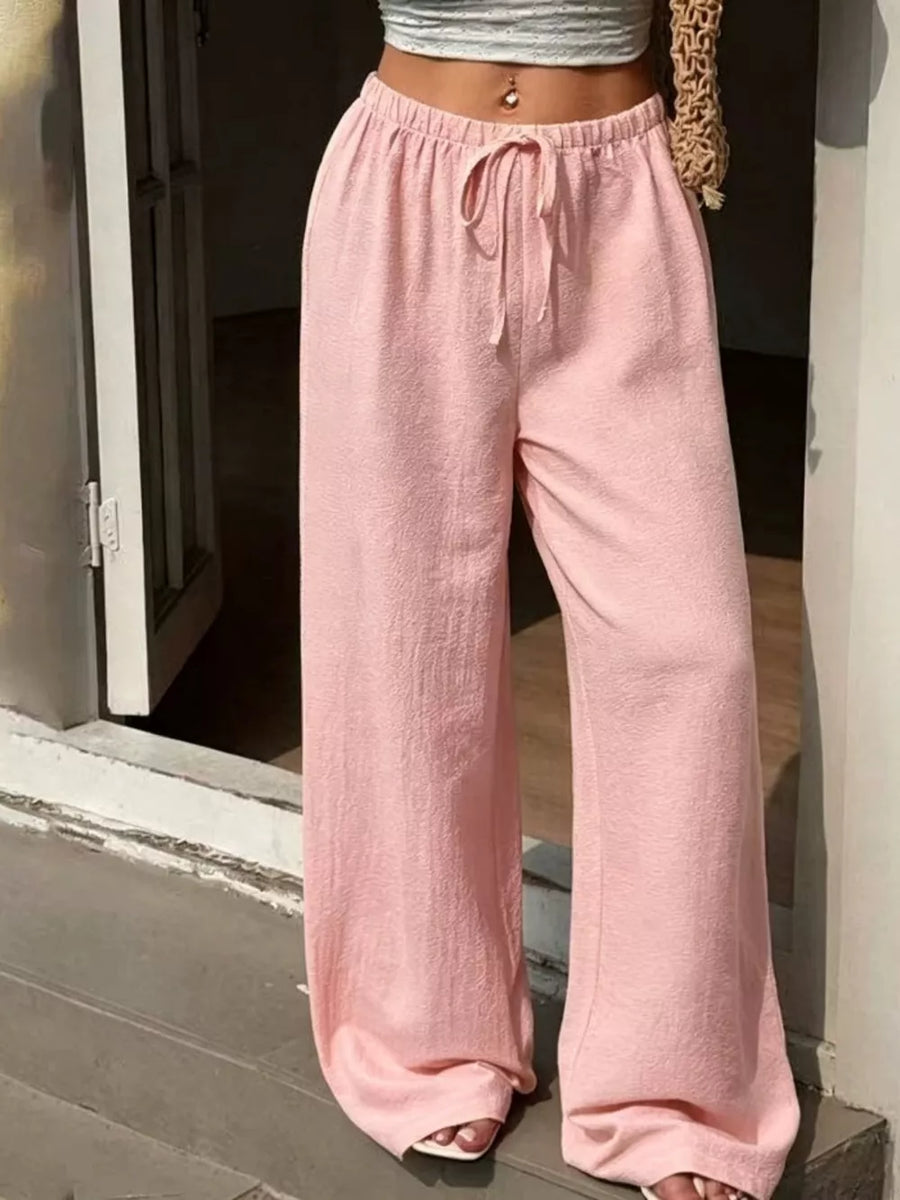 Pink wide-leg linen pants with drawstring waist and textured fabric