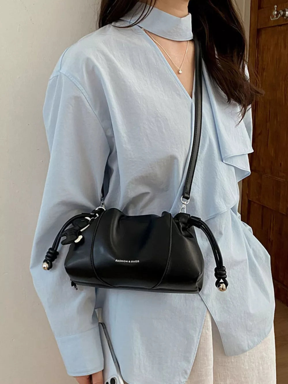 crossbody bag in black featuring drawstring closure and relaxed fit