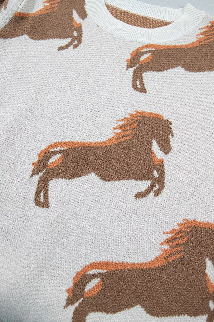 White knit sweater with allover brown and orange horse print and crew neck.