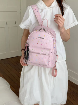 Blush pink mini backpack with colorful star print and front zipper pocket.