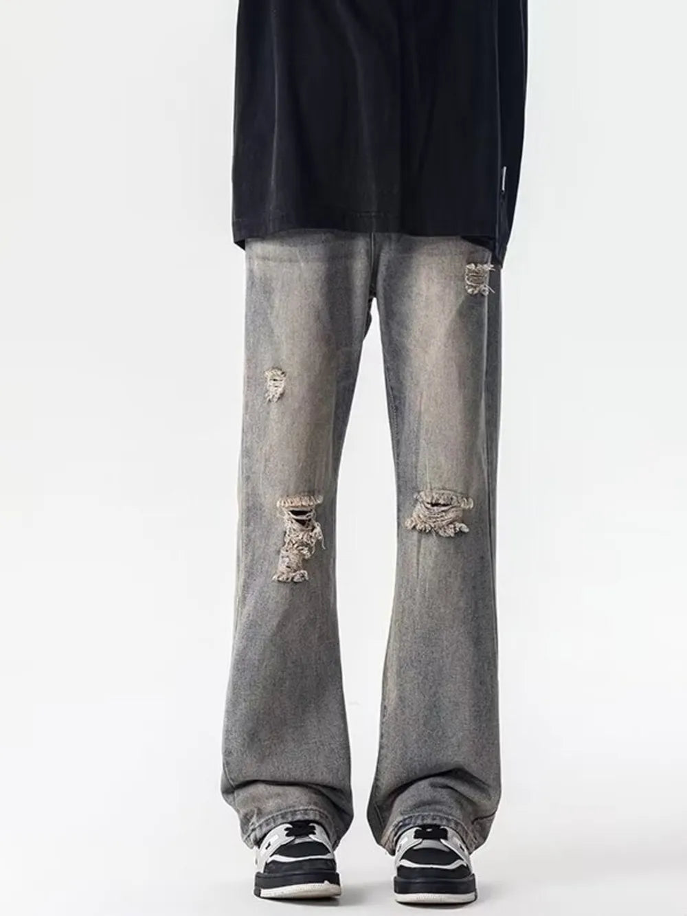 Men's distressed loose fit grey jeans with ripped details and a low tone wash.