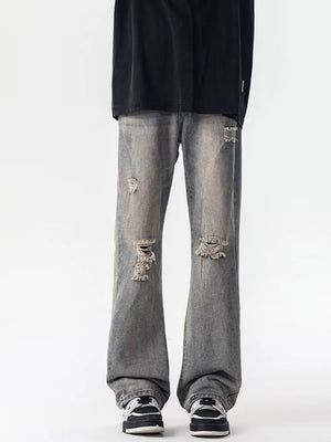 Men's distressed loose fit grey jeans with ripped details and a low tone wash.