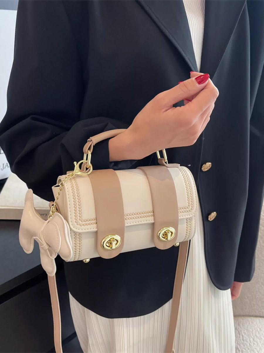 Mini PU leather crossbody bag in beige with tan straps and bow charm.