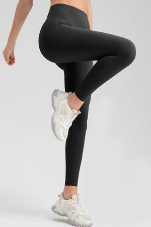 Black high rise leggings with a seamless waistband, shown on a model wearing white sneakers.