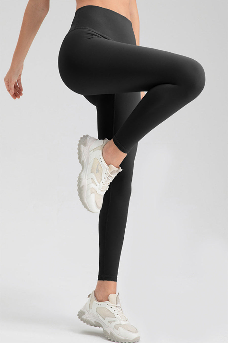 Black high rise leggings with a seamless waistband, shown on a model wearing white sneakers.