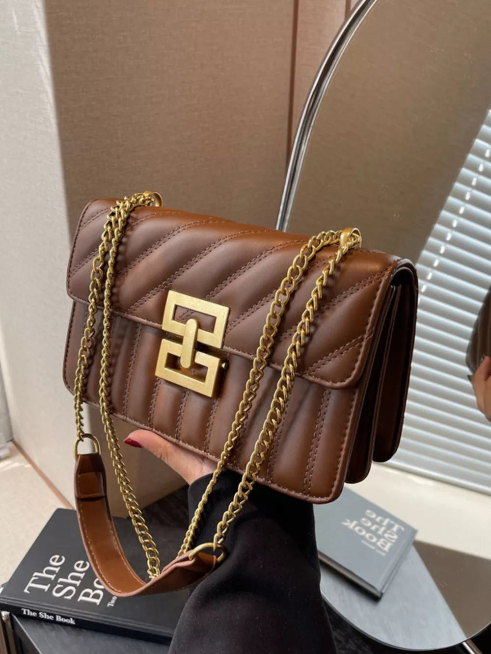 Chic quilted crossbody bag in brown with gold chain and clasp detail.