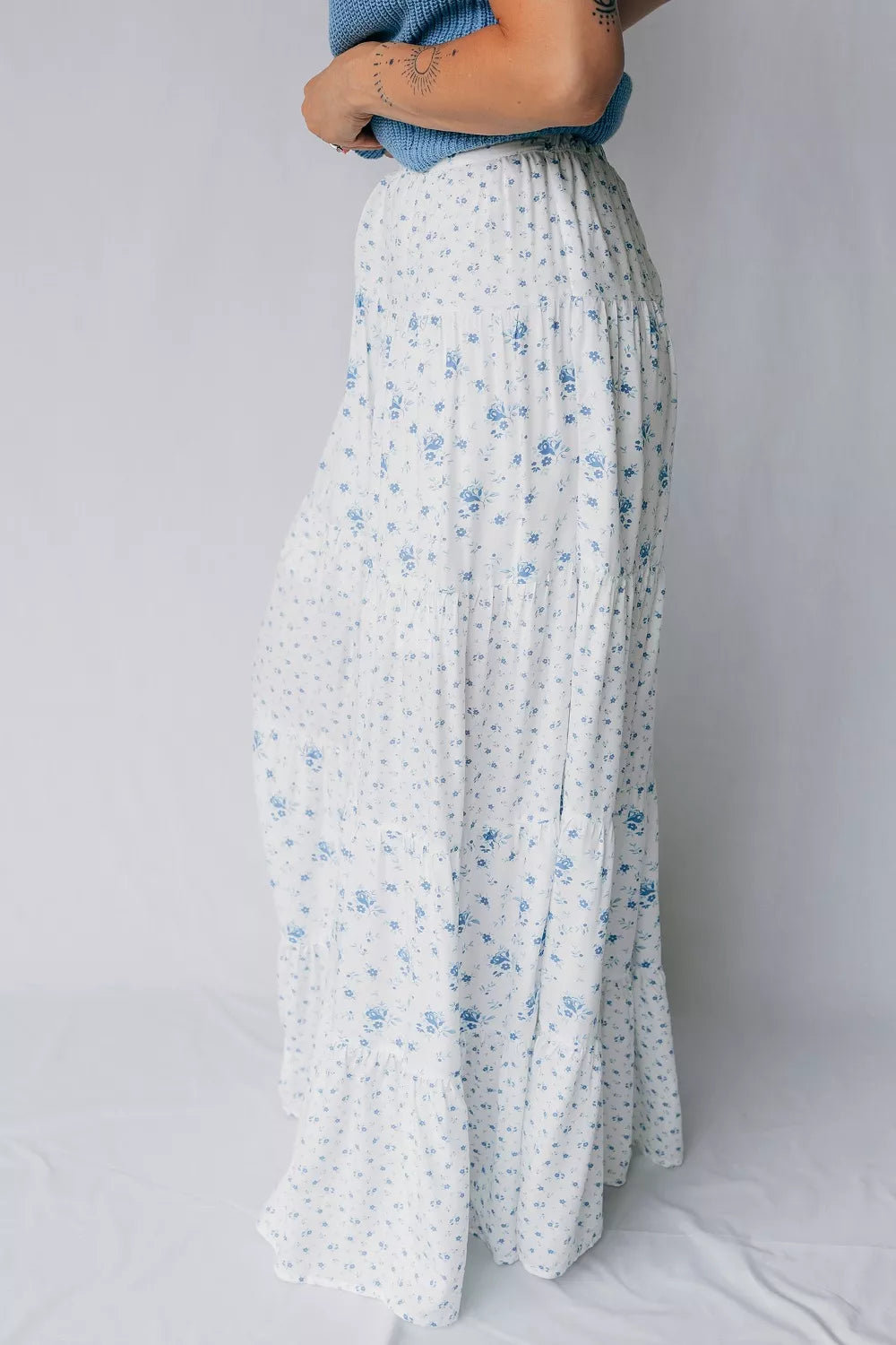 Bohemian tiered maxi skirt with blue floral print on white fabric.