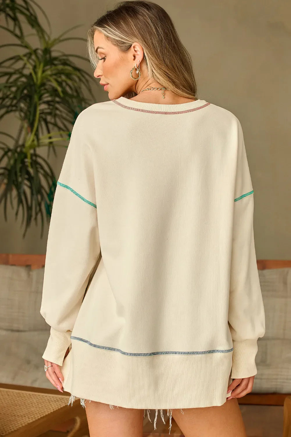 Beige graphic cross stitch sweatshirt with contrast stitching detail and raw hem.
