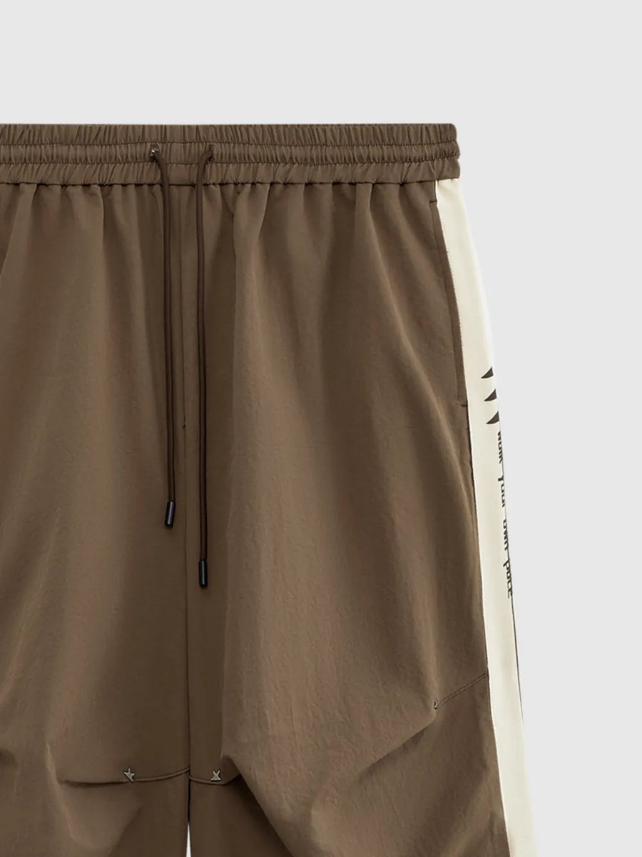 Brown relaxed fit sweatpants with cream side stripe and drawstring waist.