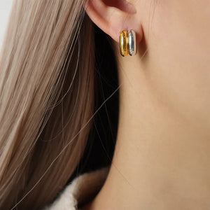 Dual-tone sculptural C-hoop earrings in gold and silver, a modern statement accessory.